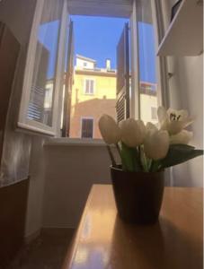 un vaso di fiori su un tavolo davanti a una finestra di Casa Rella - Camera Green a Bologna