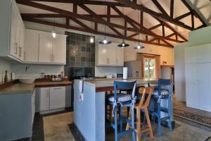 a kitchen with white cabinets and blue bar stools at Aloe Arbour Self-catering cottages in White River
