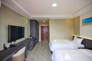 een hotelkamer met 2 bedden en een flatscreen-tv bij Belmond Hotel 贝尔曼酒店 in Koror