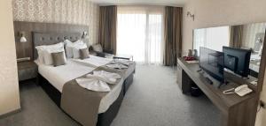 Habitación de hotel con cama grande y TV en Katalina SPA Resort en Tsigov Chark