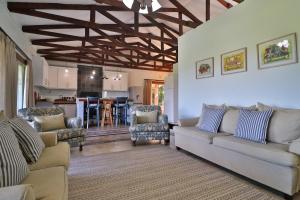 a living room with two couches and a kitchen at Aloe Arbour Self-catering cottages in White River