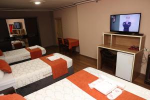 a hotel room with three beds and a flat screen tv at Adana Saray Hotel in Adana