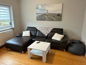a living room with a black leather couch and a red lighthouse at Ferienhaus Paulsen in Breklum