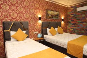 two beds in a hotel room with red wallpaper at Adana Saray Hotel in Adana