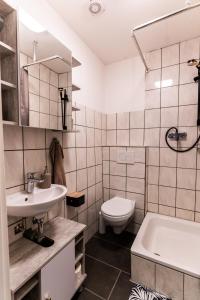 a bathroom with a sink and a toilet and a tub at Ferienwohnung Haus am See in Kaufungen