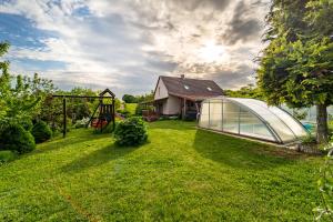 a yard with a greenhouse and a house at Kútvölgy Vendégház in Vác