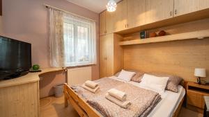 a bedroom with a bed with a television and towels at Kútvölgy Vendégház in Vác