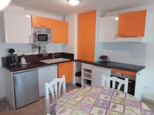 una cucina con armadi arancioni, tavolo e sedie di Lavandoule a Gréoux-les-Bains