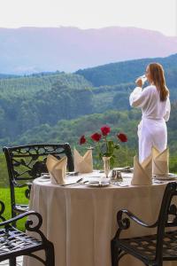 Coach House Hotel & SPA Tzaneen في تزانين: امرأة تشرب كأس من النبيذ على طاولة