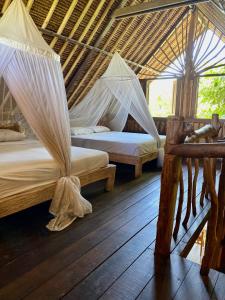 2 Betten in einem Zimmer mit Moskitonetzen in der Unterkunft Flower Bud Bungalow Balangan in Jimbaran