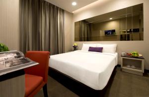 a bedroom with a large white bed and a red chair at V Hotel Bencoolen in Singapore