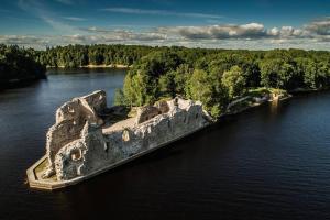 an old castle in the middle of a river at Mākslas studija Koknesē in Koknese