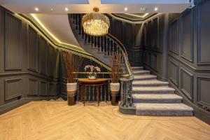 a staircase in a room with black walls and a chandelier at Charlotte House Residence by COQOON in Manchester