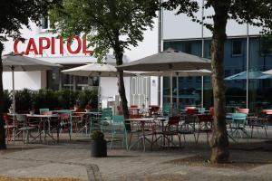 a group of tables and chairs with umbrellas in front of a building at Das Neue CAPITOL in Bad Berleburg