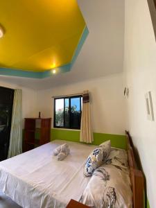 a bedroom with a large bed with a yellow ceiling at Residencia Gemma in Siquijor