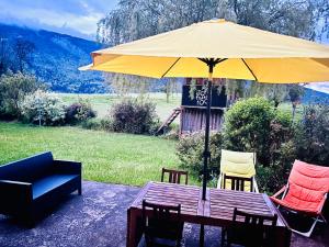 une table en bois avec un parasol et des chaises jaunes dans l'établissement Évasion familiale entre Lac Annecy & Massif Bauges, à Saint-Eustache