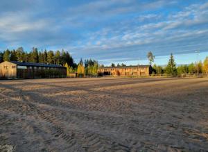 桑德維肯的住宿－Ofvansjö Gård , Enkel stuga för övernattning på ett fd militärområde，一块空的泥土,有建筑背景