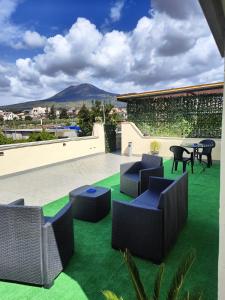 a patio with chairs and tables on green grass at Vesuvius Dream in Boscotrecase