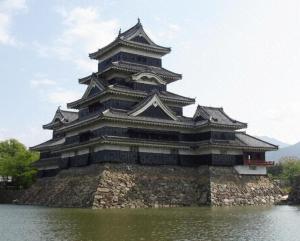a large building on the side of a body of water at Garden Hotel Matsumoto in Matsumoto