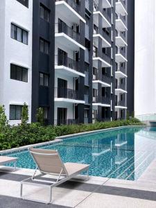 a chair and a swimming pool in front of a building at Cozy n New Eco Style in Teluk Panglima Garang