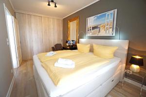 a bedroom with a large white bed with yellow sheets at Villa To Hus _ strandnah in Neuhof