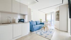 a kitchen and a living room with a blue couch at Prywatne Apartamenty Sun & Snow w Wave z basenem in Międzyzdroje