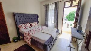 a bedroom with a bed with a blue headboard and a window at Gee's Neat Apartment in Mombasa CBD-Parking in Mombasa