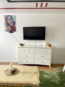 uma sala de estar com televisão numa cómoda branca em Westfield Gardens Apartment - 3 bedrooms em Goodmayes