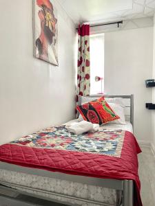 a bedroom with a bed with a red quilt at Westfield Gardens Apartment - 3 bedrooms in Goodmayes