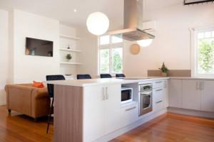 Una cocina con gabinetes blancos y una mesa y un sofá. en Family-Friendly Comfort, en Kings Park