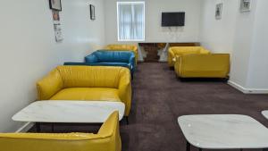 a waiting room with yellow and blue couches and a tv at Hotel Blackpool in Blackpool