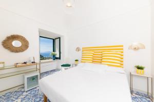 a white bedroom with a large bed and a window at La Gloriette in Capri