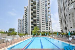 a swimming pool with chairs and a tall building at Park Tzameret 3BR Panoramic by HolyGuest in Tel Aviv