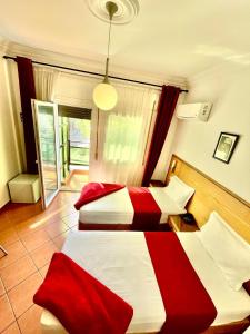 two beds in a room with red and white at Sary's Hotel in M'diq