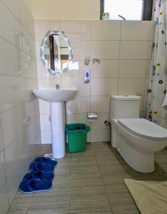 uma casa de banho com um lavatório, um WC e um espelho. em Oslo Gardens Bed & Breakfast em Entebbe
