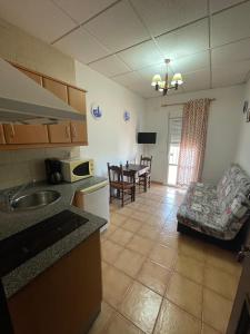Una cocina y una sala de estar con mesa y sillas. en Finca La Tacita - Jazmín, en Conil de la Frontera