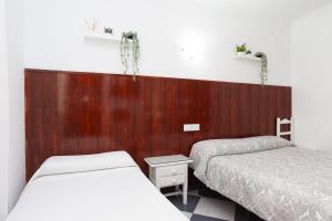 a bedroom with two beds and a wooden wall at Hostal Restaurante La Giralda in Rota