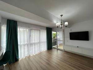 uma sala de estar com uma televisão de ecrã plano e cortinas verdes em Tatarasi Wolf Apartaments and Studios Iasi em Iaşi