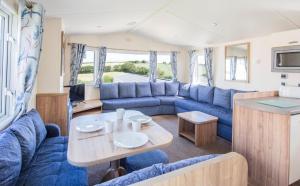 a caravan living room with a blue couch and a table at Trelawne Manor Holiday Park in Looe