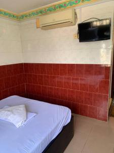 uma cama num quarto com uma parede de azulejos vermelhos em Ditar Guest House S em Battambang