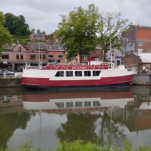 un barco rojo y blanco sentado en el agua en Gîte Le Sambre, en Thuin