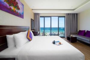 a hotel room with a large white bed with a balcony at Alani Hotel & Spa in Da Nang