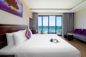 una camera d'albergo con un grande letto bianco e un balcone di Alani Sea View Hotel a Da Nang