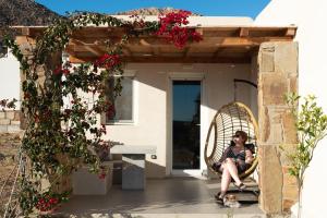 a woman sitting in a chair on the porch of a house at Megusta Mykonos in Tourlos