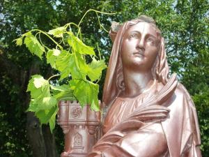 Eine Statue einer Frau mit einer Pflanze davor. in der Unterkunft Maison Hôtes Villa Sainte Barbe in Mirecourt
