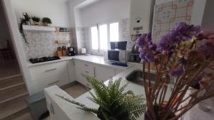 a kitchen with a sink and a vase of purple flowers at La Casa del Bienestar in Cabra