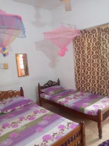 two beds in a room with purple sheets at Kunam Beach Rest Inn in Batticaloa
