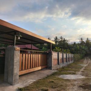 a house with a wooden fence next to a road at Bogenvil villa in Tanjung