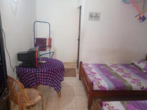a small room with two beds and a table and a tv at Kunam Beach Rest Inn in Batticaloa