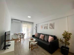 Apartamento Beli Málaga في بينالمادينا: غرفة معيشة مع أريكة سوداء وطاولة